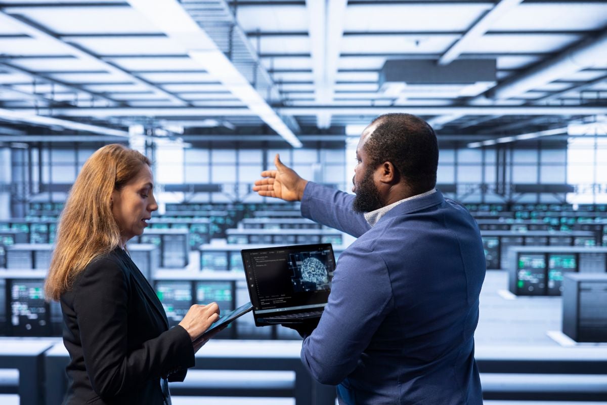 Team of technicians in data center using laptop to visualize ai